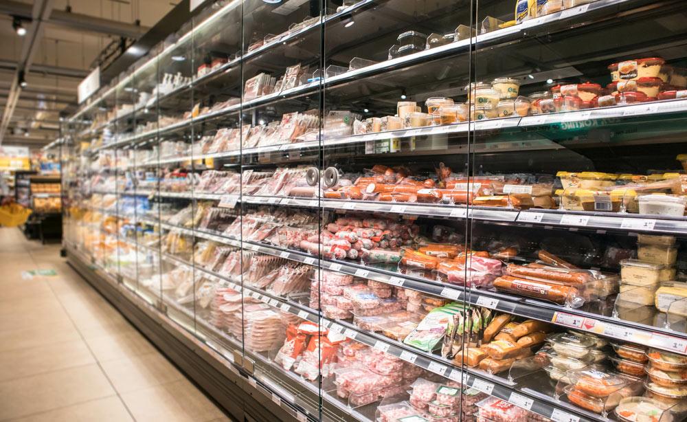 Refrigerated grocery display case filled with packaged meats, cheeses, and prepared foods